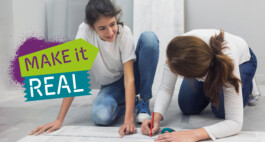 Zwei Mädchen malen hocken am Boden, besprechen etwas und schreiben auf einen Flipchartpapierbogen. Foto Credit: Stock-Fotografie-ID: 930109606 // istockphoto.com // bearbeitet + Logo „MAKEitREAL“ 